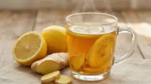 Tisana calda allo zenzero e limone con fettine fresche su un tavolo di legno