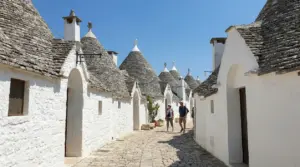 Strada acciottolata tra i trulli di Alberobello con alcune persone che passeggiano