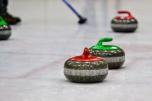 Giocatori di curling durante una partita olimpica mentre lanciano la stone sul ghiaccio