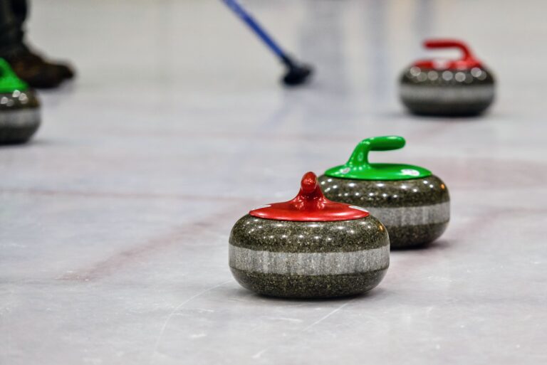 Giocatori di curling durante una partita olimpica mentre lanciano la stone sul ghiaccio